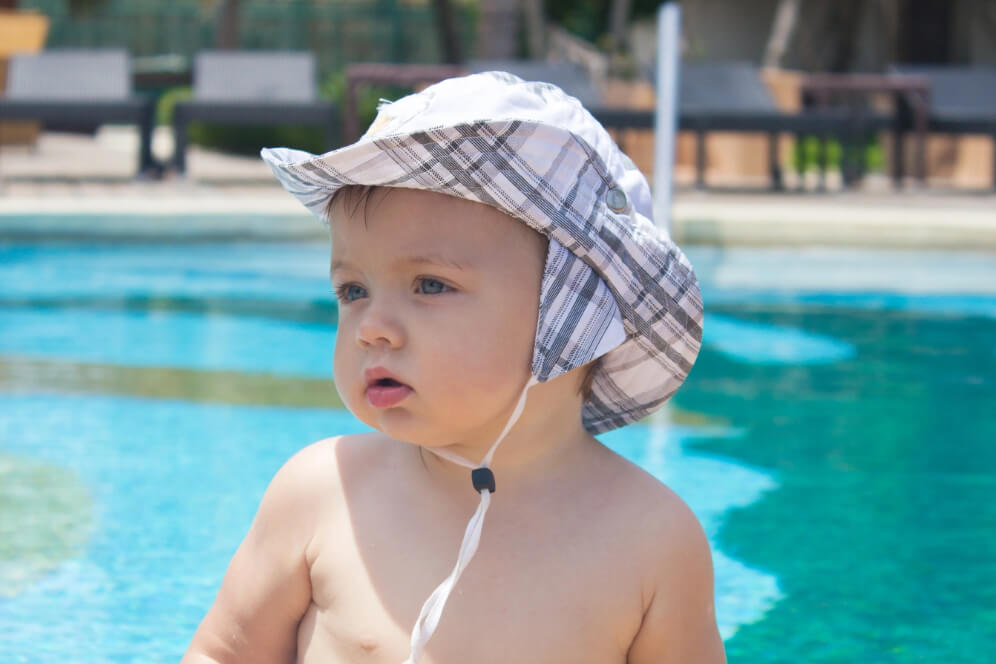 copil mic la piscina cu palarie cu protectie solara in carouri