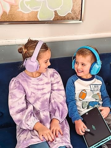 fetita si baietel cu casti antifonice stau pe o canapea si discuta