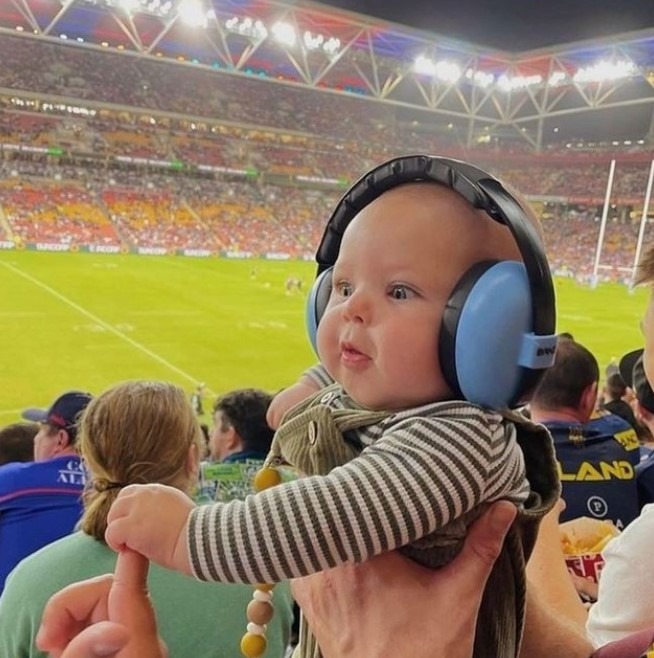 imagine cu bebe cu casti antifonice pe cap, la meci de fotbal