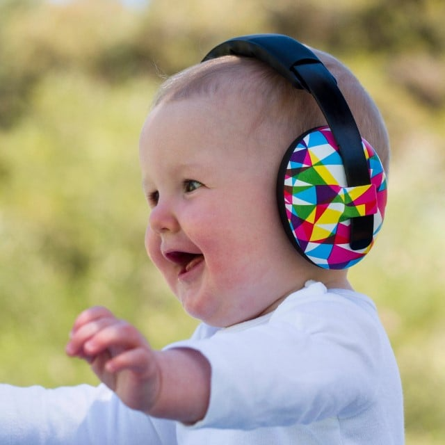 copil mic fericit care poarta casti antifonice si alearga in natura protejat de zgomote