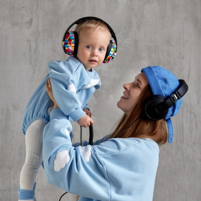 mama cu copil in brate care are casti antifonice pe cap