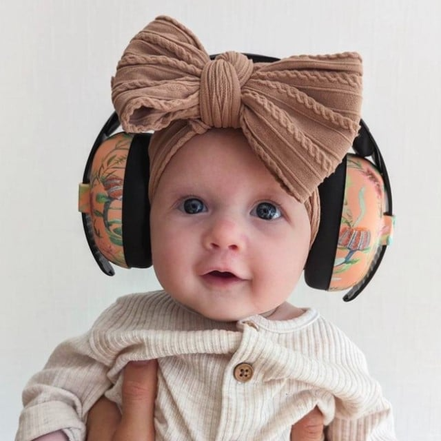fetita mica bebe cu funda si casti antifonice pe cap