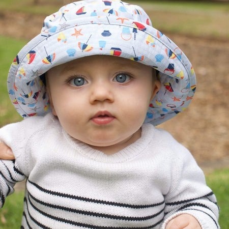 portret de bebelus cu ochii albastri si palarie de protectie solara asortata