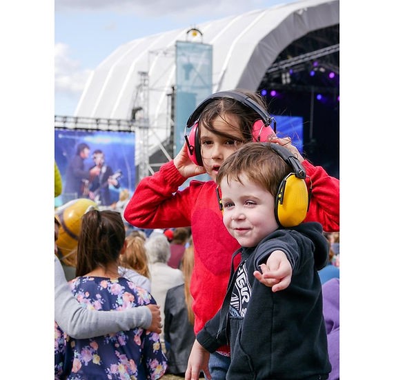 doi copii cu casti antifonice pe cap la un concert
