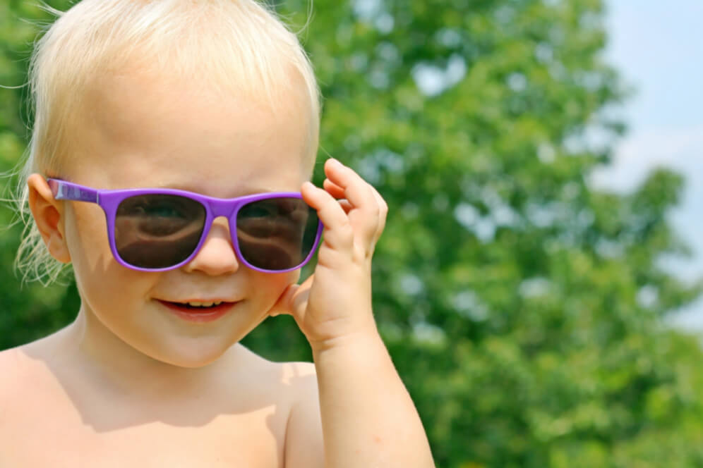 bebelus fericit cu ochelari mov de soare si zambet