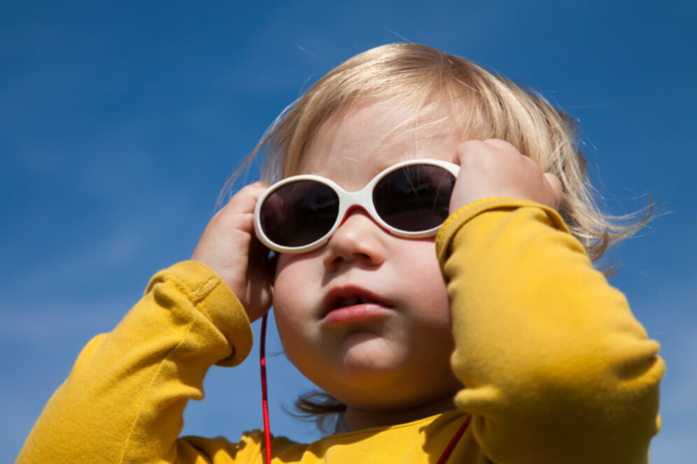 portret de bebelus cu mainile pe ochelarii de soare 