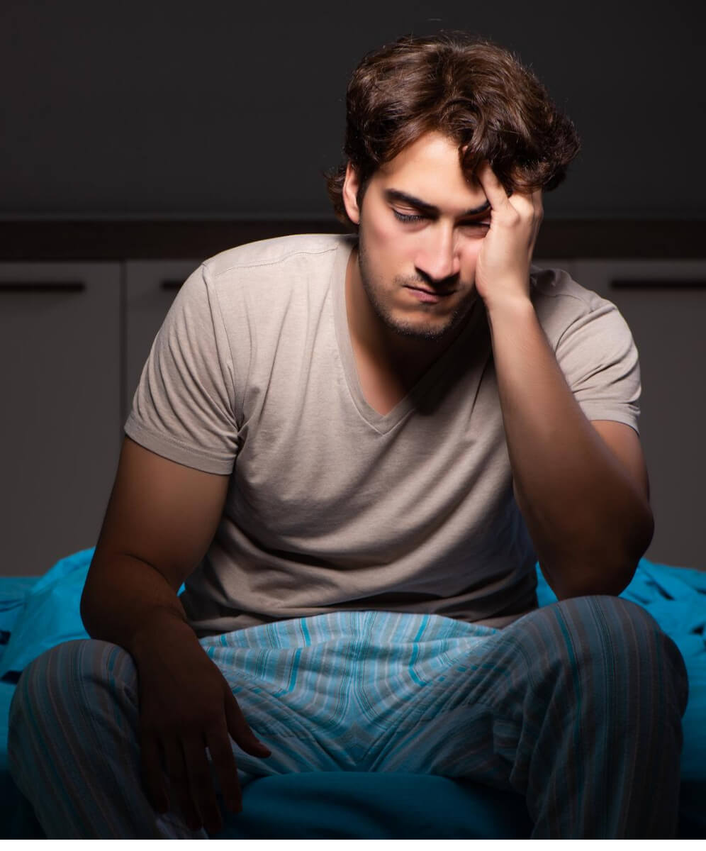 barbat langa pat cu mana pe cap pare ca nu poate sa doarma