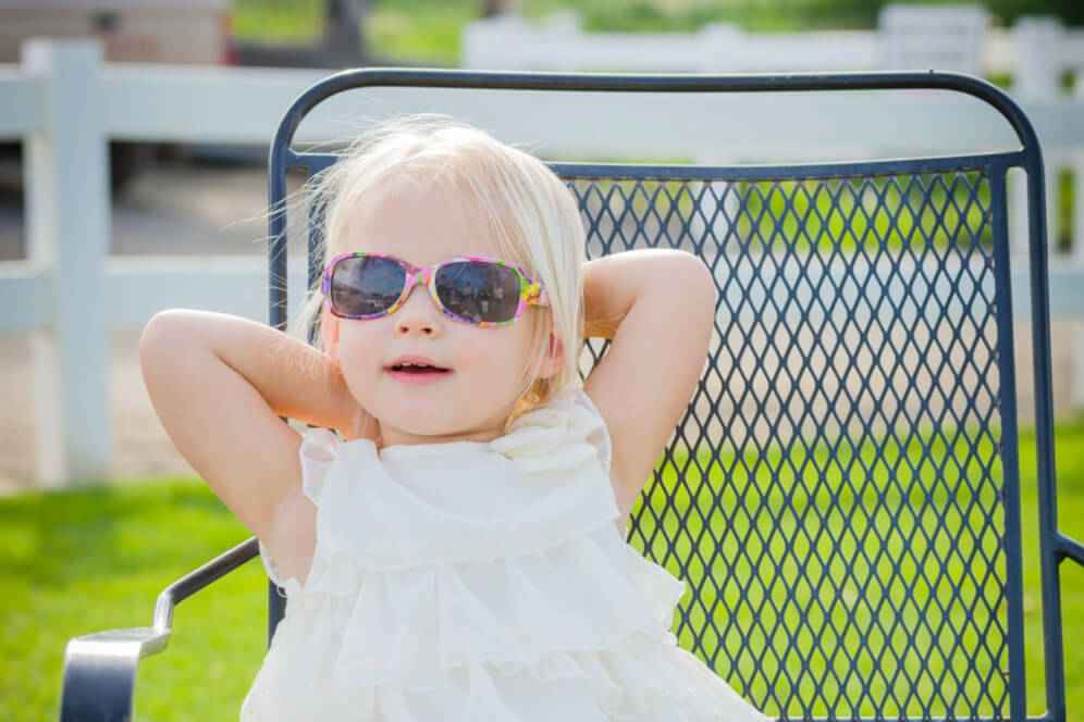 fetita relaxata sta pe scaun la soare cu ochelari de soare pe ochi