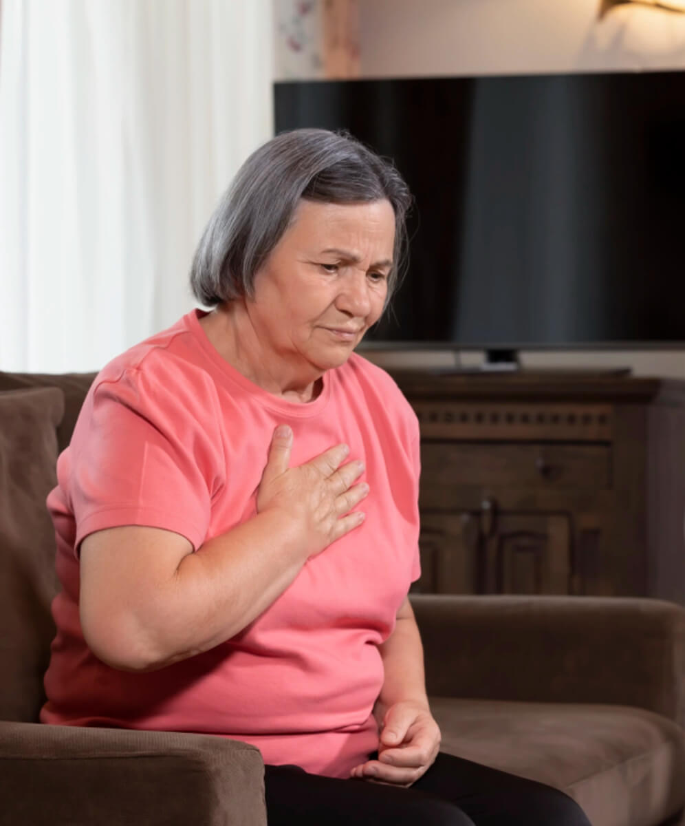 femeie in varsta cu mana pe inima, pare ca o doare inima