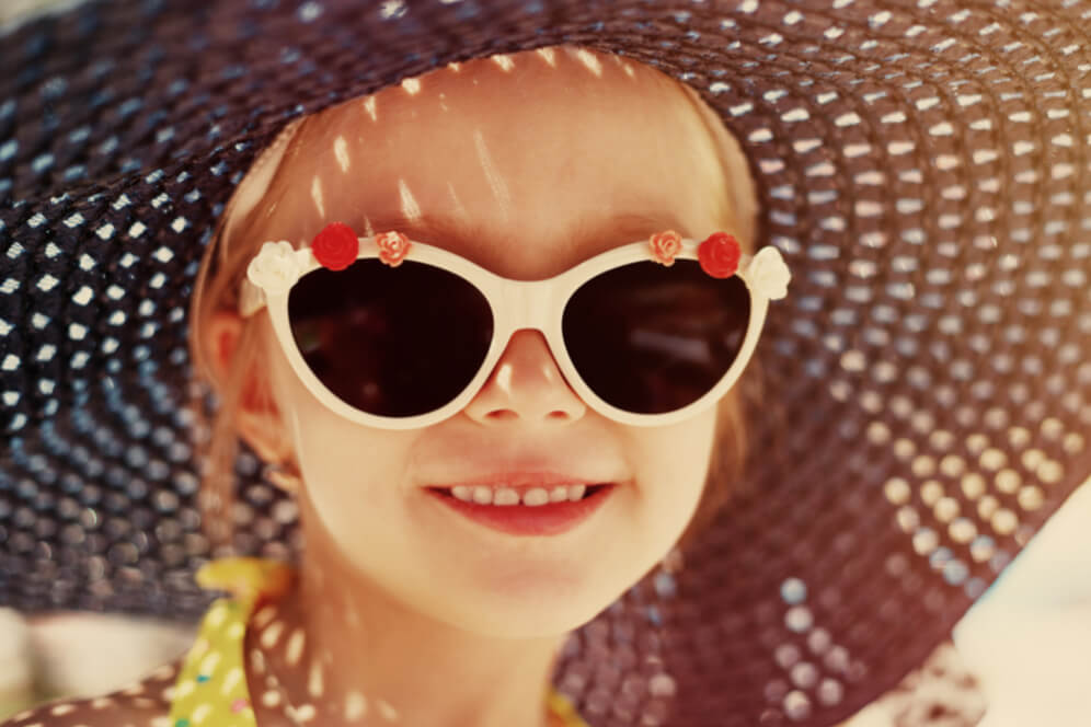 fetita cu ochelari de soare albi cu floricele si zambet dulce